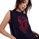 Woman wearing a navy blue sleeveless sweater with a red lobster design
